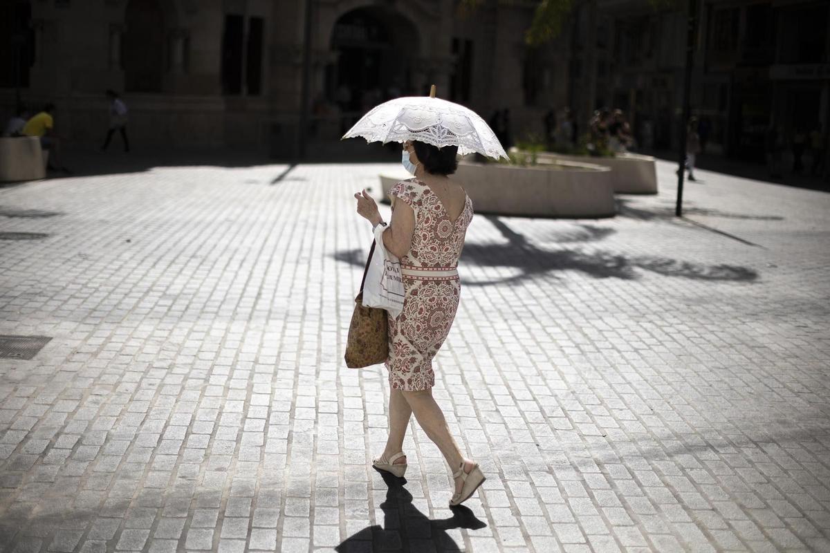 Una mujer se protege este martes del intenso calor en una calle del centro histórico de Valencia.