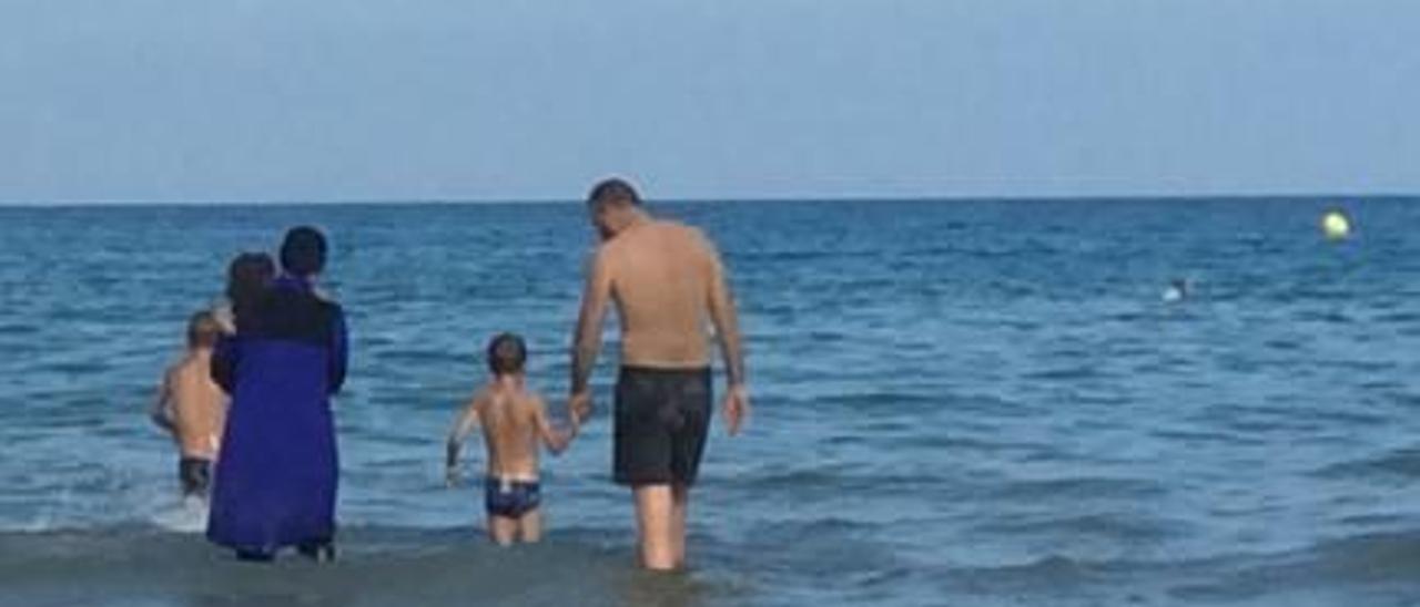 Una mujer metiéndose en el agua con el bañador islámico.