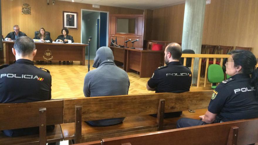 El acusado, que está en prisión provisional, ayer, custodiado por policías en el juicio en Vigo. // Fdv