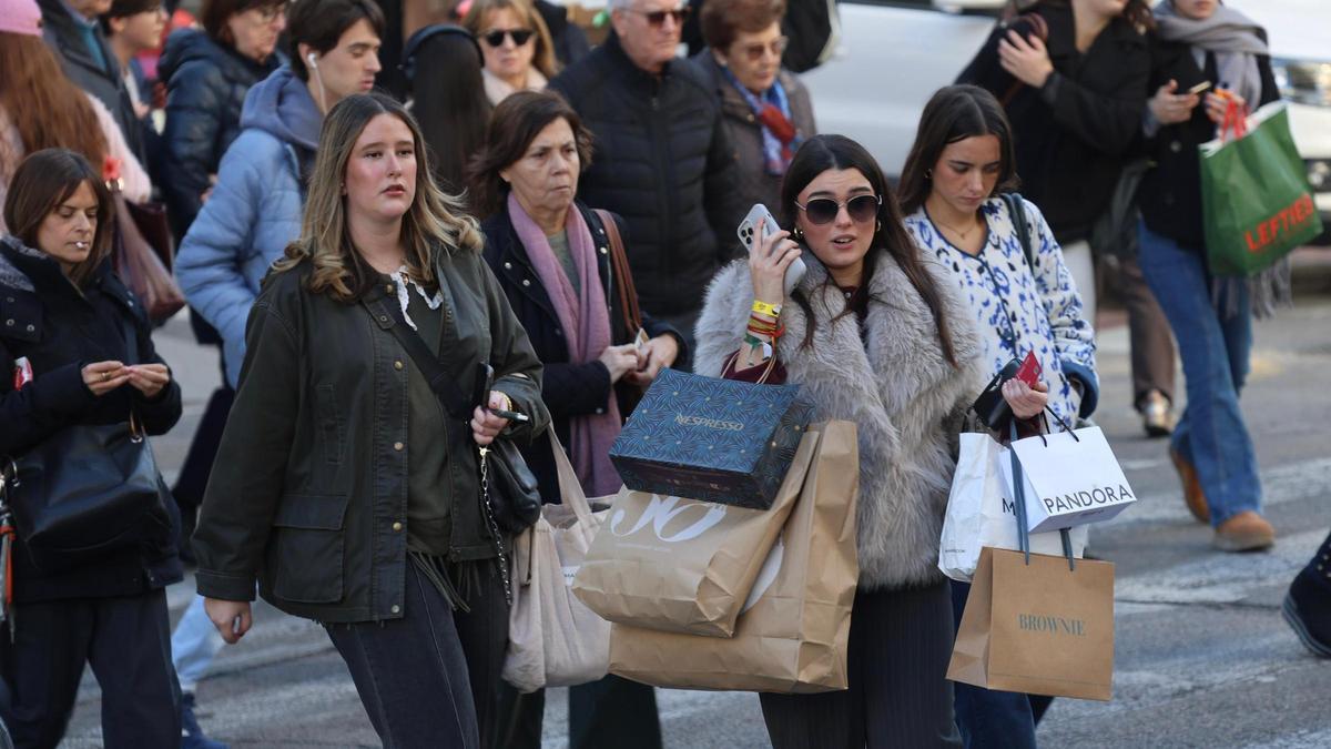Personas con bolsas por el centro de València, durante la jornada del 'Black Friday'.