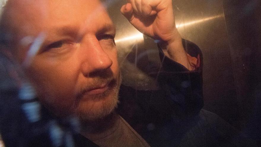 Julian Assange saluda a los fotógrafos desde un vehículo policial.