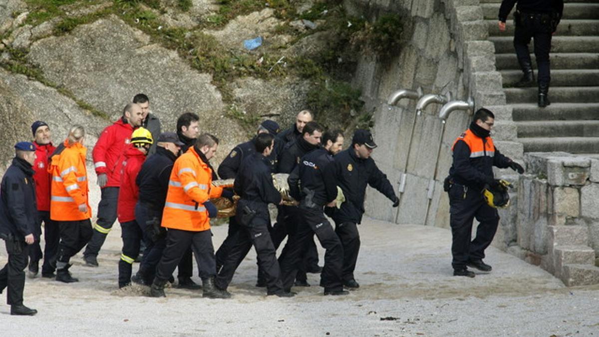 Agentes de la Policía Nacional retiran de la playa coruñesa de Orzán el cuerpo de uno de los agentes desaparecido en el mar el pasado viernes.