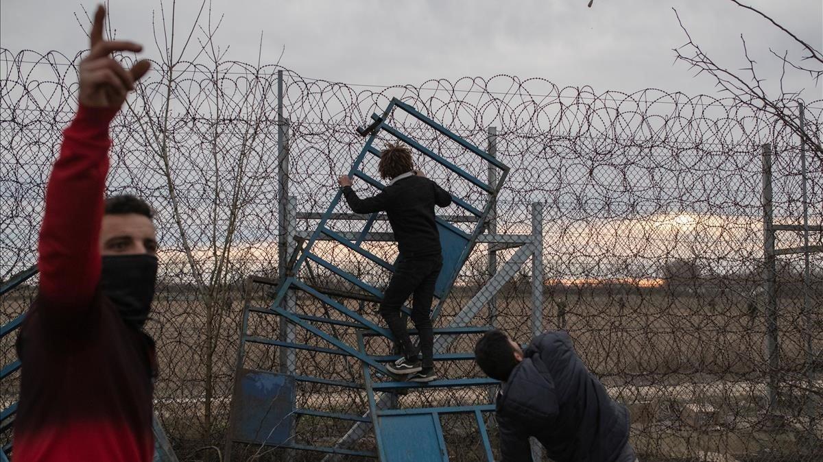 zentauroepp52661123 migrants climb fence at the border as they clash with greek 200306193758