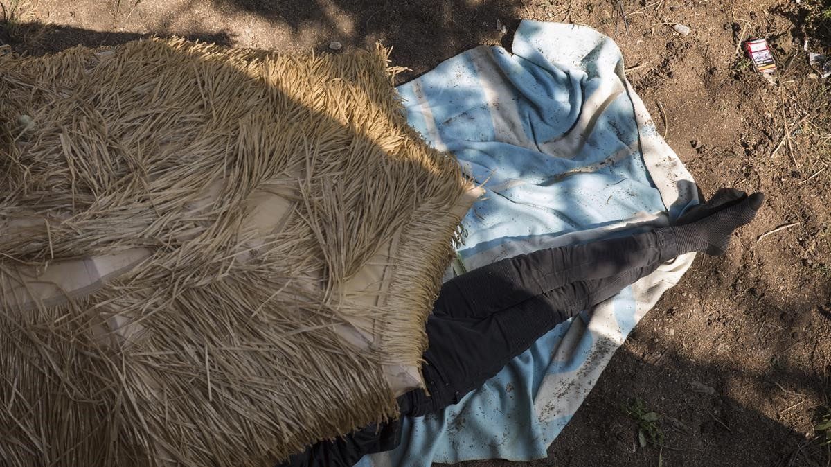Menas: un niño de la calle duerme bajo una sombrilla en un campamento de la montaña de Montjuïc
