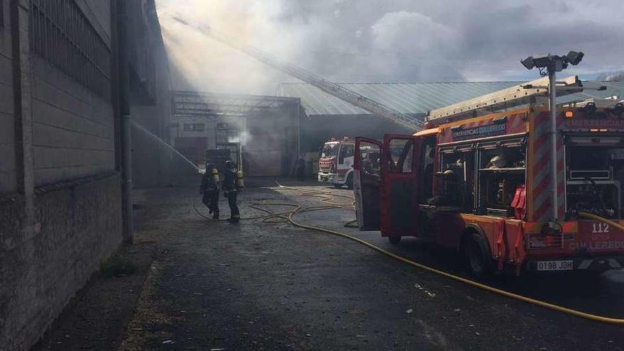 Efectivos de emergencias, durante la extinción de las llamas, ayer, en una maderera de Sigrás.