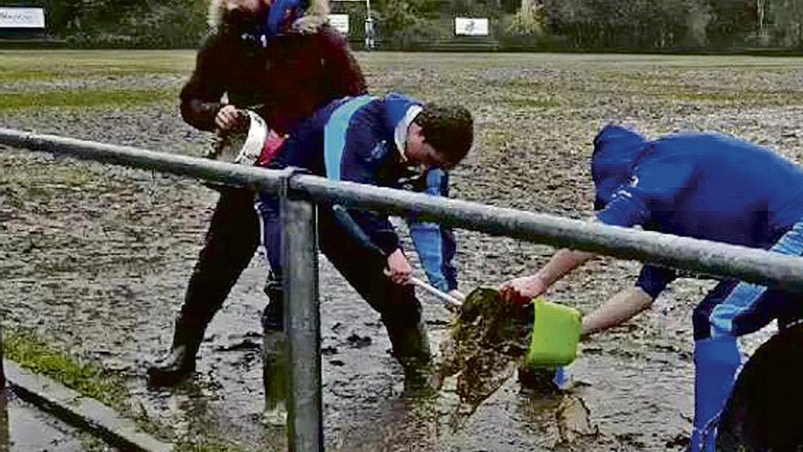 Dos personas achican agua del campo de rugby.