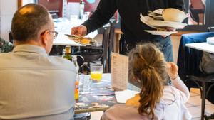 Un camarero limpia una mesa en un bar de Barcelona.