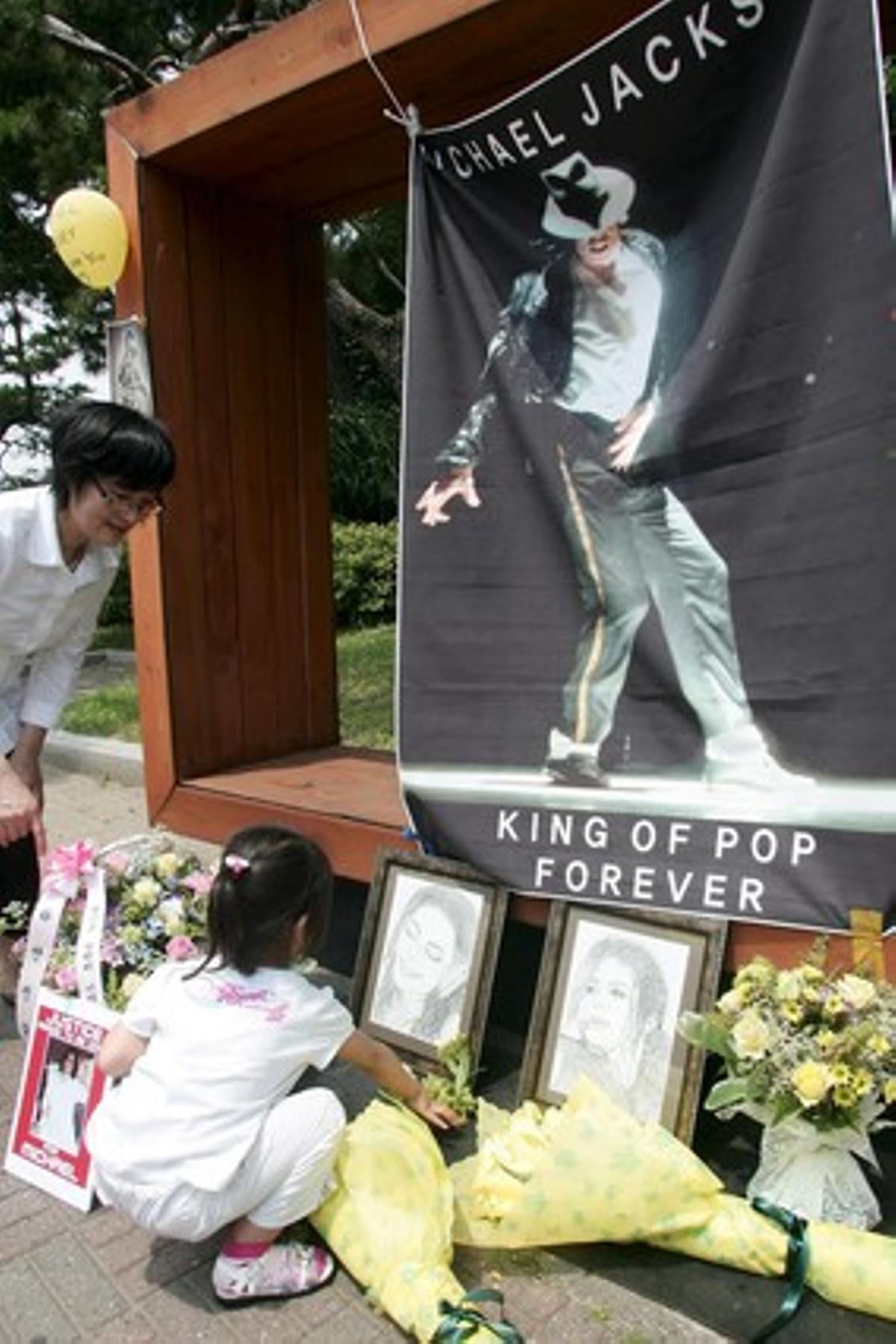 Una nena diposita flors, al costat de diversos rams, espelmes, fotos i cartes de fans en el primer aniversari de la mort del cantant nord-americà, el 2010.