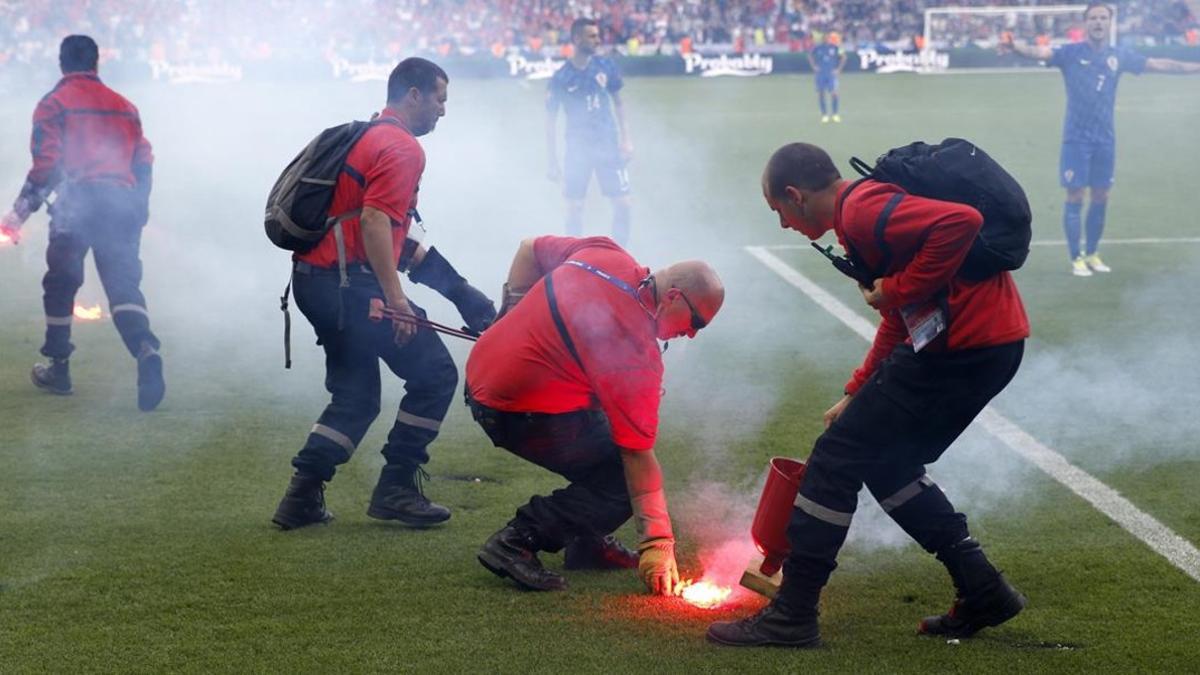 Empleados del estadio Geoffroy Guichard de Sain-Étienne recogen las bengalas lanzadas por los seguidores croatas