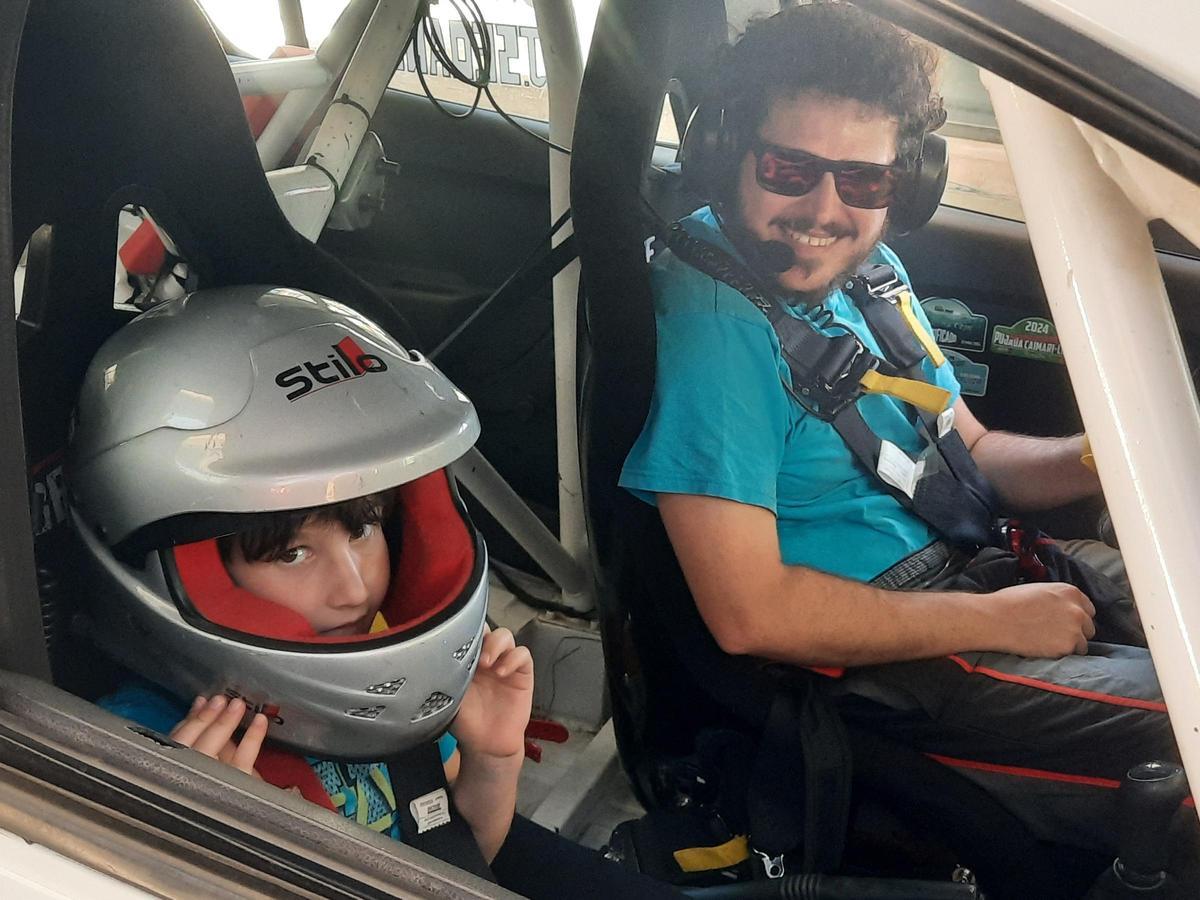 Un piloto posa con un niño en un coche de competición.