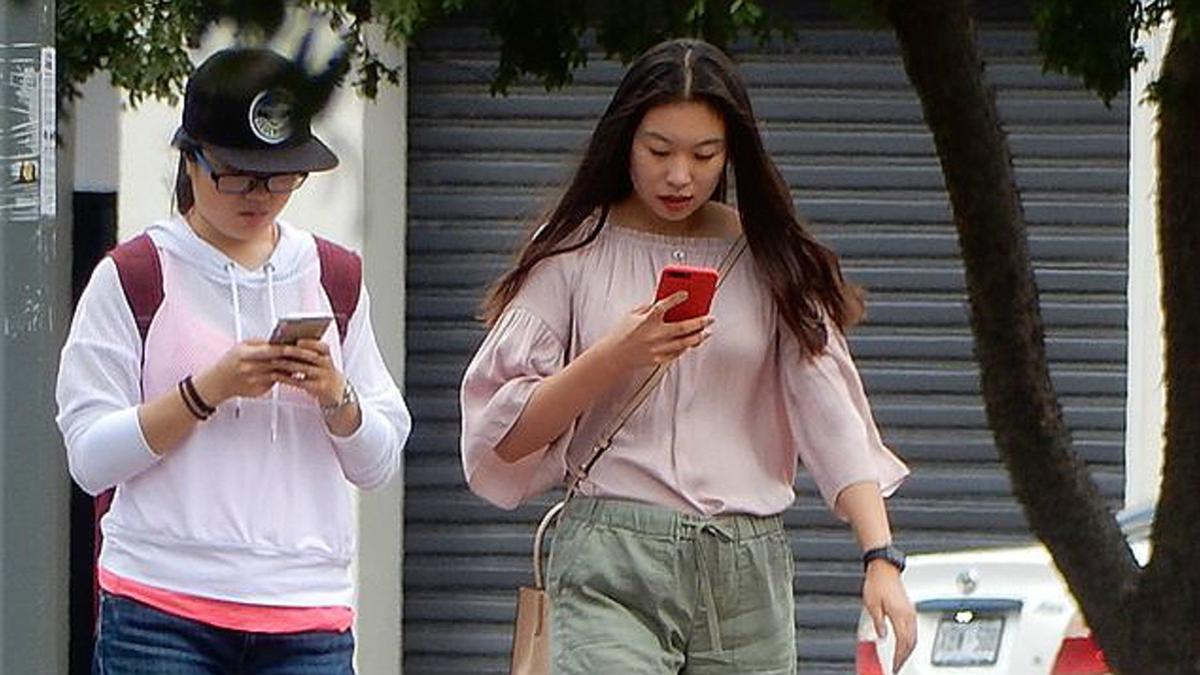 Dos chicas pasean por la calle sin hablarse y absortas en sus teléfonos móviles