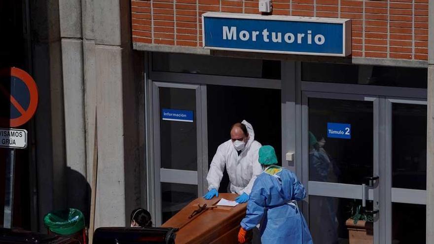 Técnicos sanitarios manejan el cuerpo de una víctima de covid-19 en Madrid.