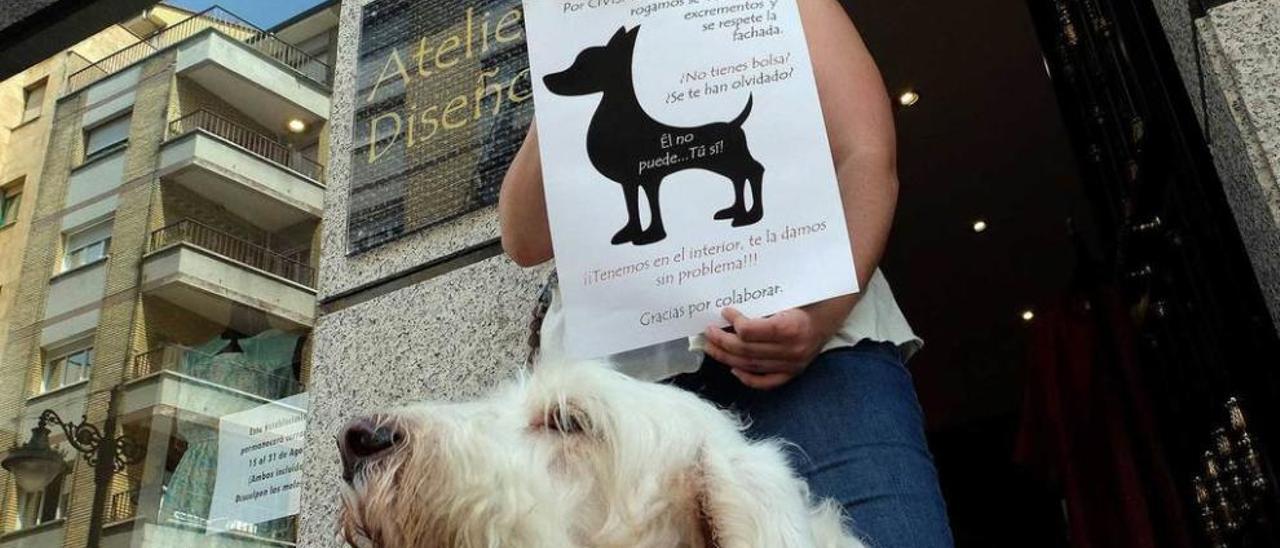 Minerva Losa muestra el cartel que pide civismo a los dueños de animales a la puerta de su negocio.