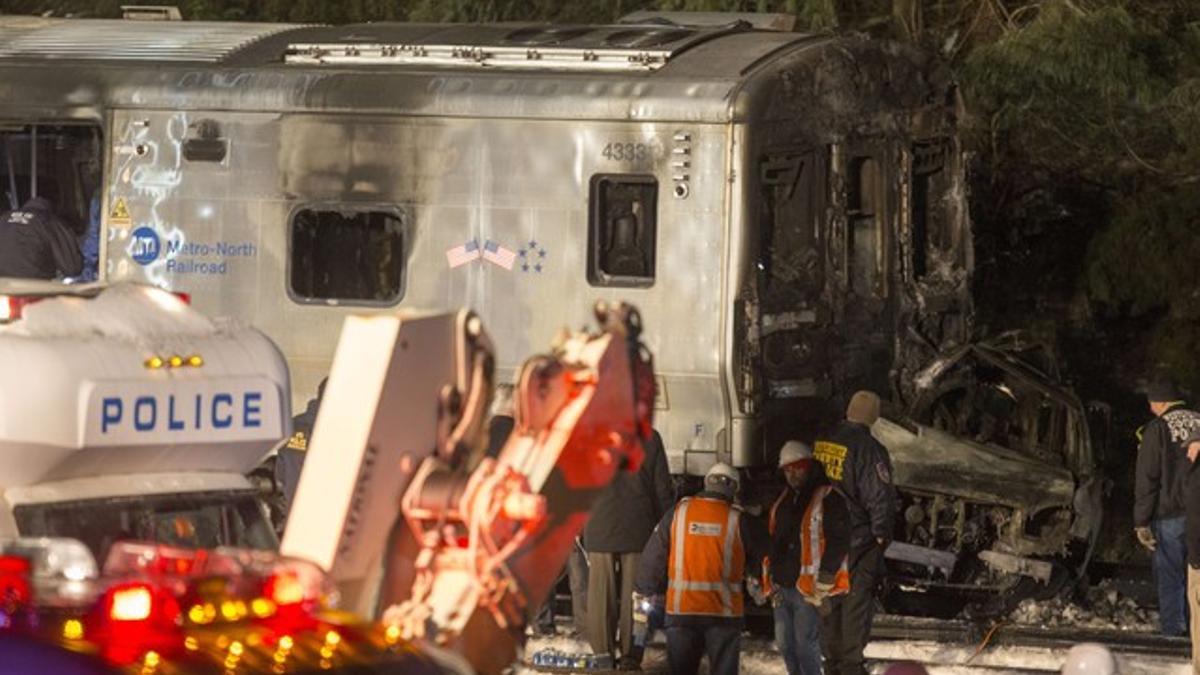 Los servicios de emergencias, ante la locomotora del tren y el vehículo, totalmente calcinado, en Valhalla (Nueva York).