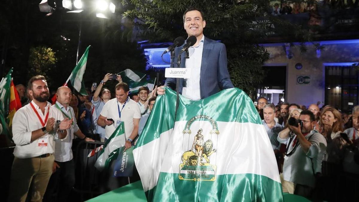 Moreno celebra su mayoría absoluta con una bandera de Andalucía.