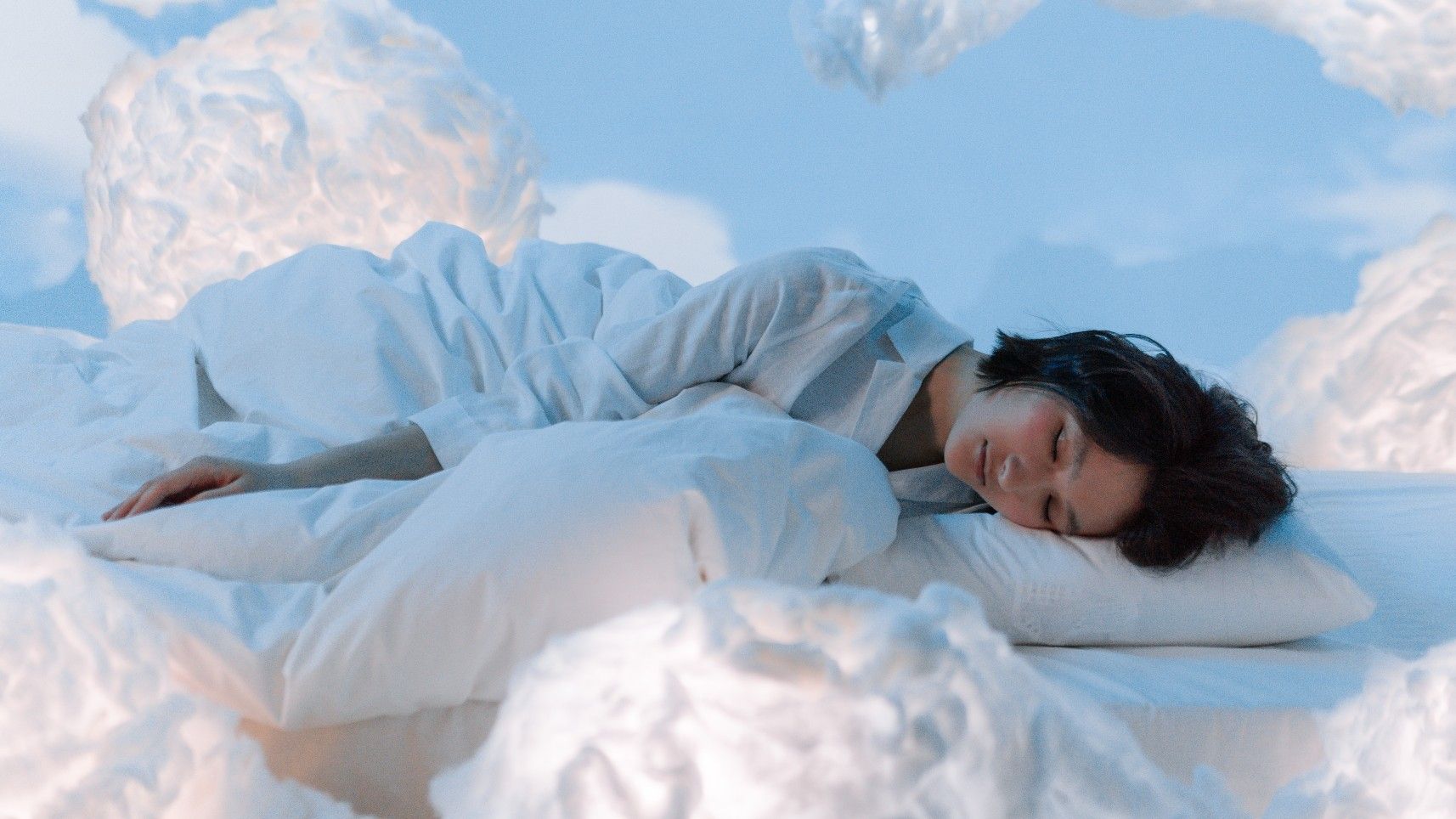 Simulación de una mujer durmiendo entre algodones o nubes blancas