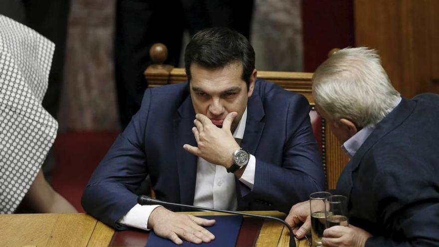 Tsipras habla con un diputado de su partido, Syriza, antes de dirigirse al Parlamento griego.
