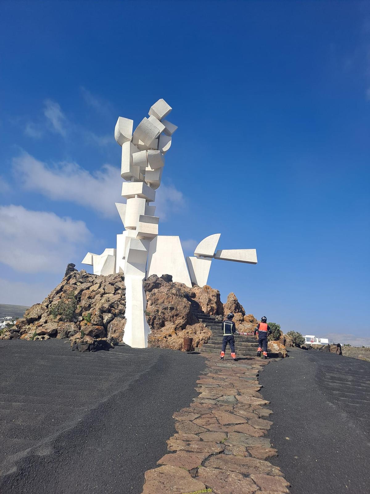 Dos bomberos junto al Monumento al Campesino, cuyas piezas superiores dañó el fuerte viento.