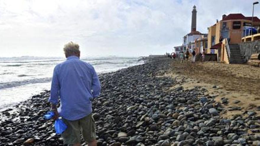 Un turista camina por la playa de Maspalomas, que ha perdido gran parte de la arena por las borrascas de la última semana.