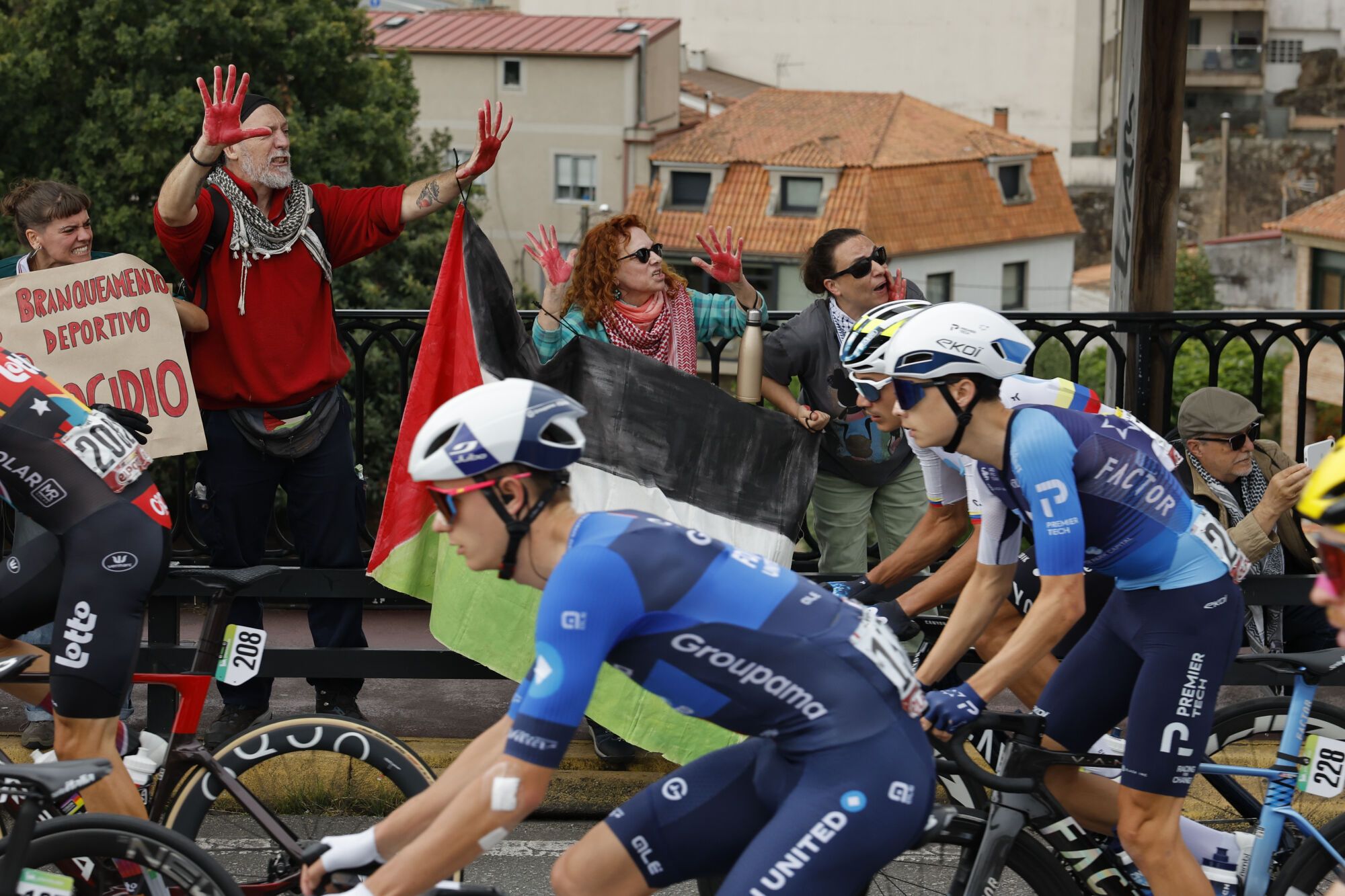 FOTODELDIA POIO (PONTEVEDRA), 09/09/2025.- Los ciclista del equipo Israel Premier Tech pasan ante las protestas propalestina durante la etapa 16 de la Vuelta Ciclista a España que se disputa este martes entre Poio y Mos-Castro de Herville (Pontevedra), de 167.9 km de recorrido. EFE/ Lavandeira Jr