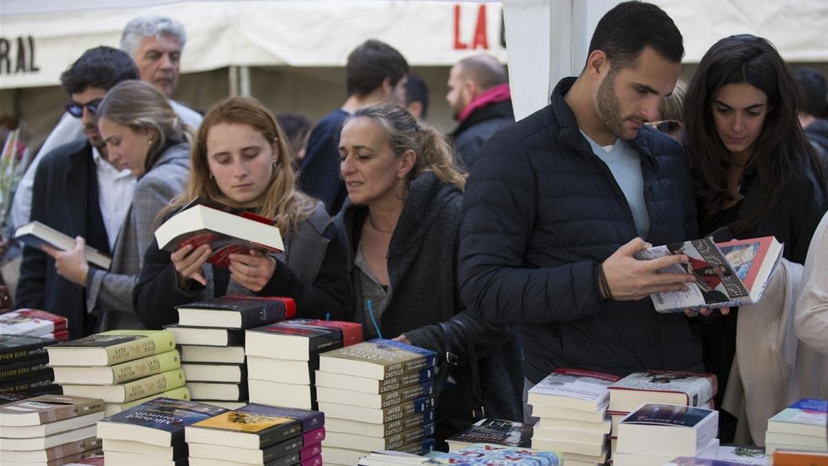 Lectores observan las últimas novedades publicadas en una parada.