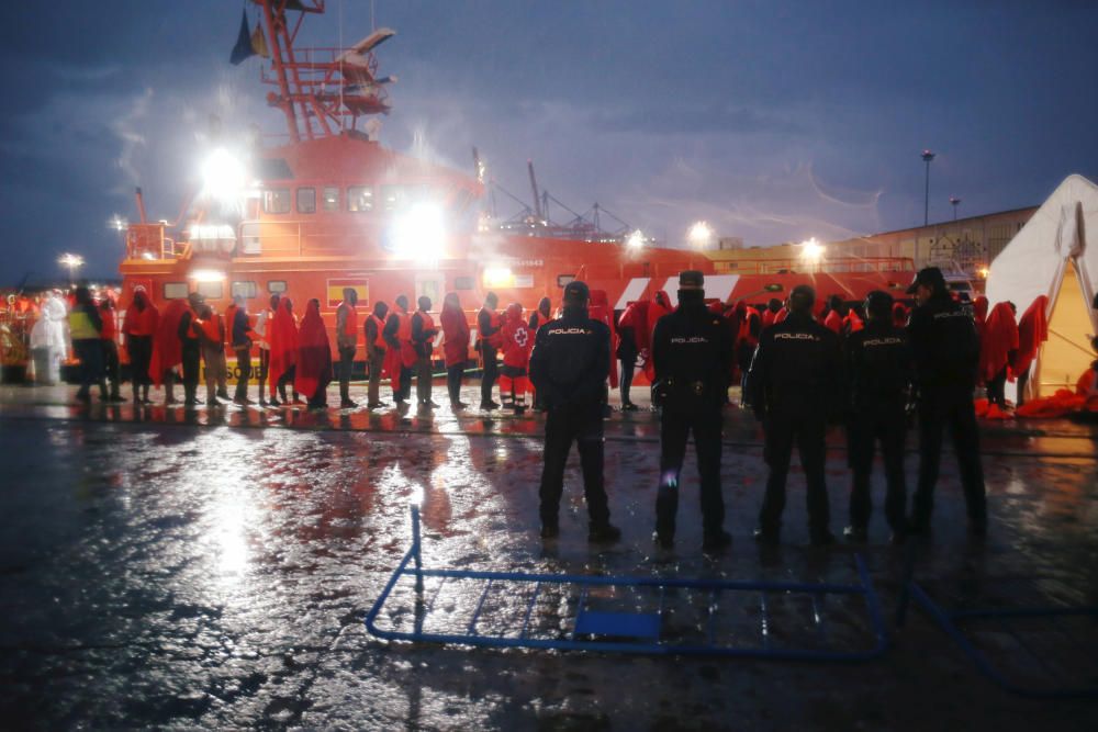 Migrants stand under the rain after disembarking ...