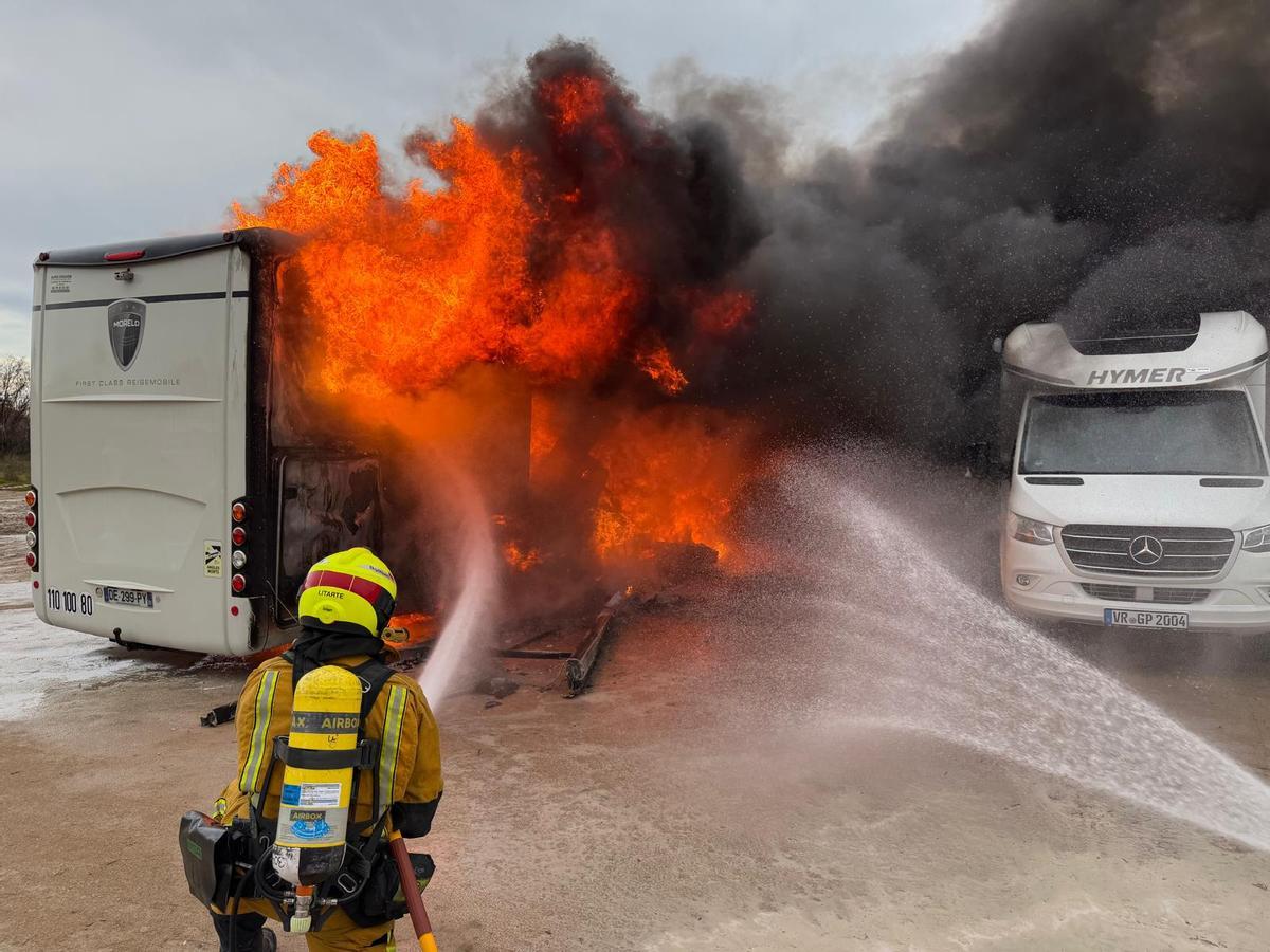 Los bomberos sofocan las llamas y rocían las autocaravana contigua para evitar que el fuego se propague