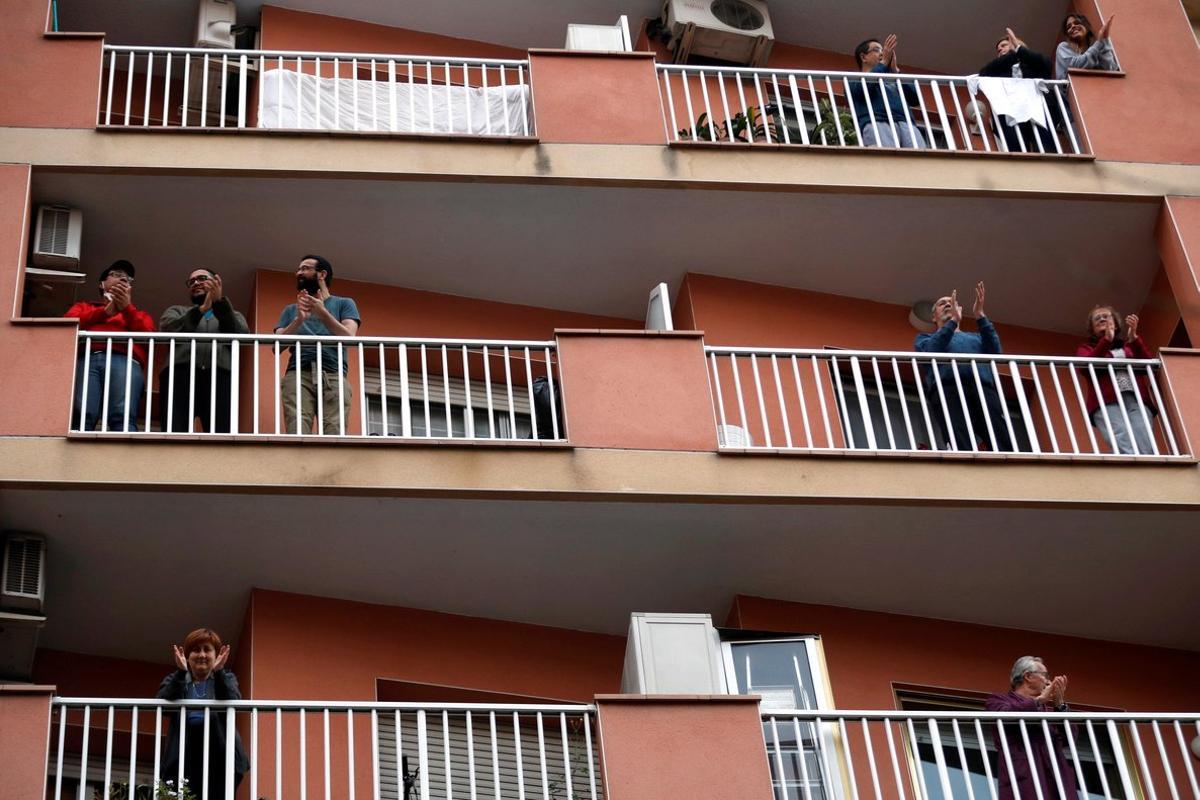 Vecinos de L’Hospitalet de Llobregat salen a sus balcones y ventanas a aplaudir a los sanitarios, el pasado 29 de marzo.