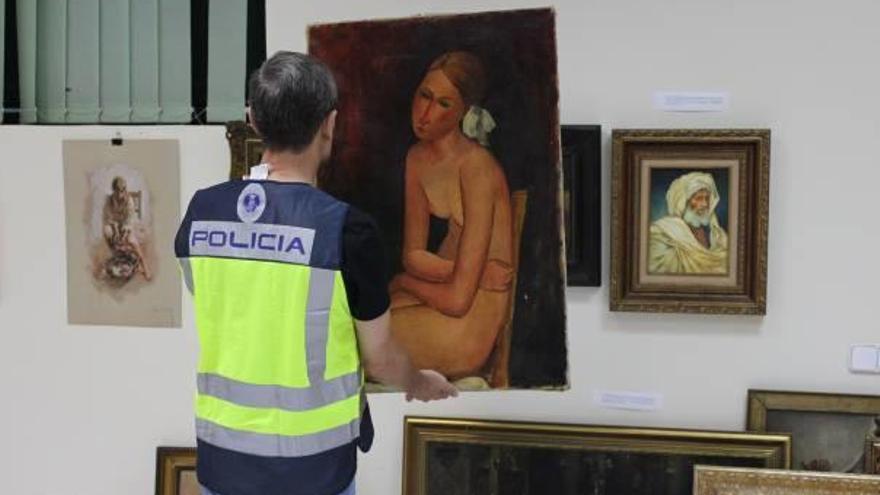 Un agente de la Policía observa el cuadro que un anticuario intentó vender como auténtico.