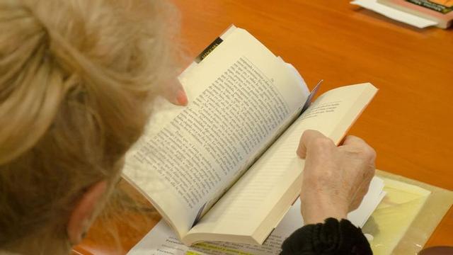 Una mujer lee un libro en una clase para personas mayores.