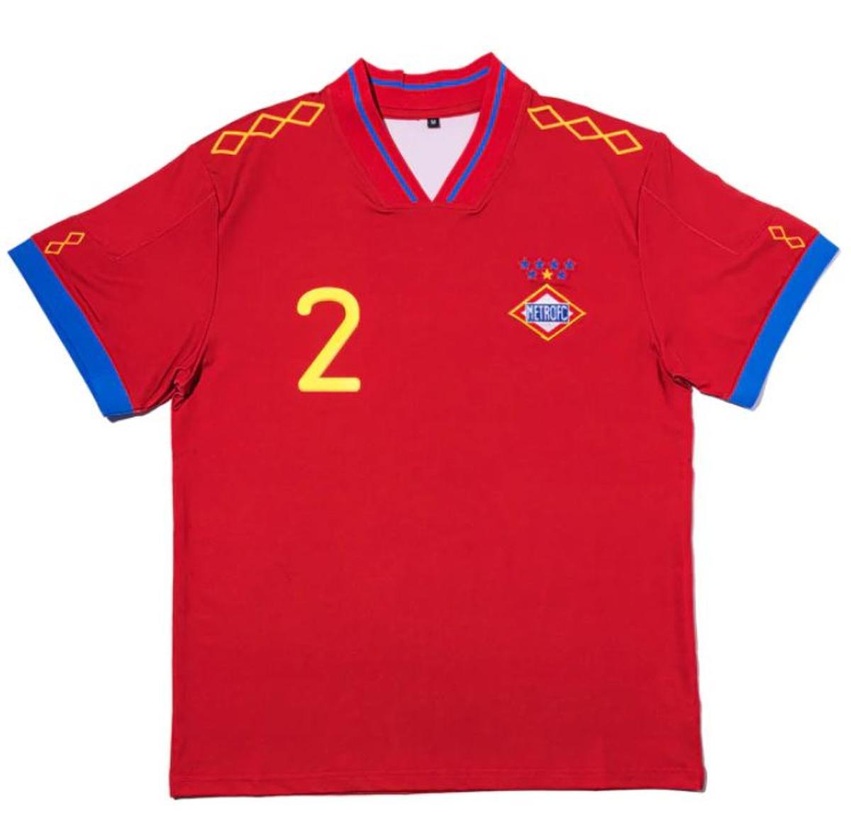 El diseño de la camiseta cuenta con un rojo intenso, detalles azules y la icónica tipografía de la equipación del Mundial de 2010