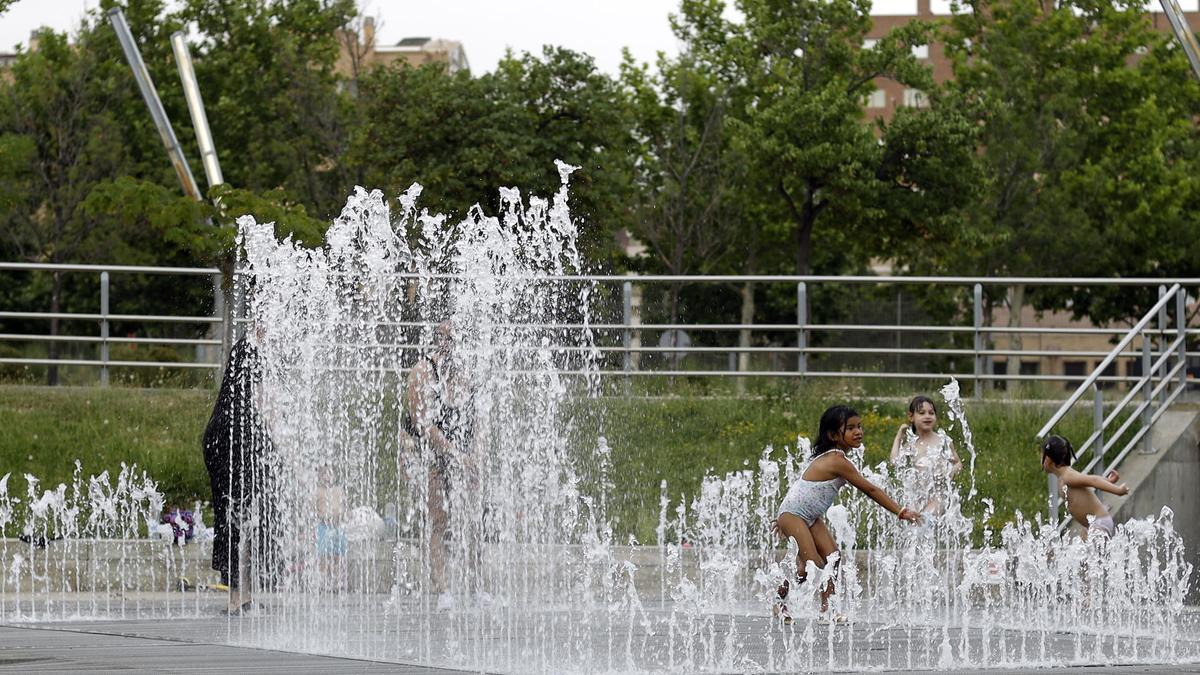 Unos niños se bañan en una fuente para combatir el calor, el pasado año.