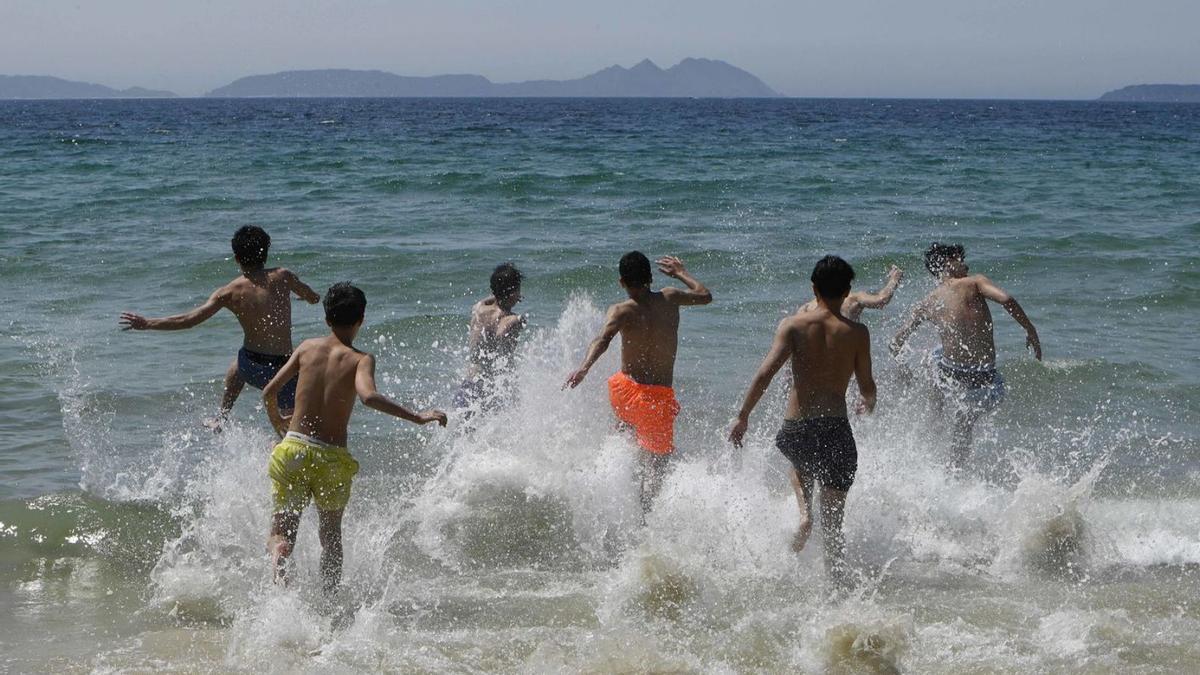 Un grupo de jóvenes entrando en el agua de Samil durante esta tórrida semana.