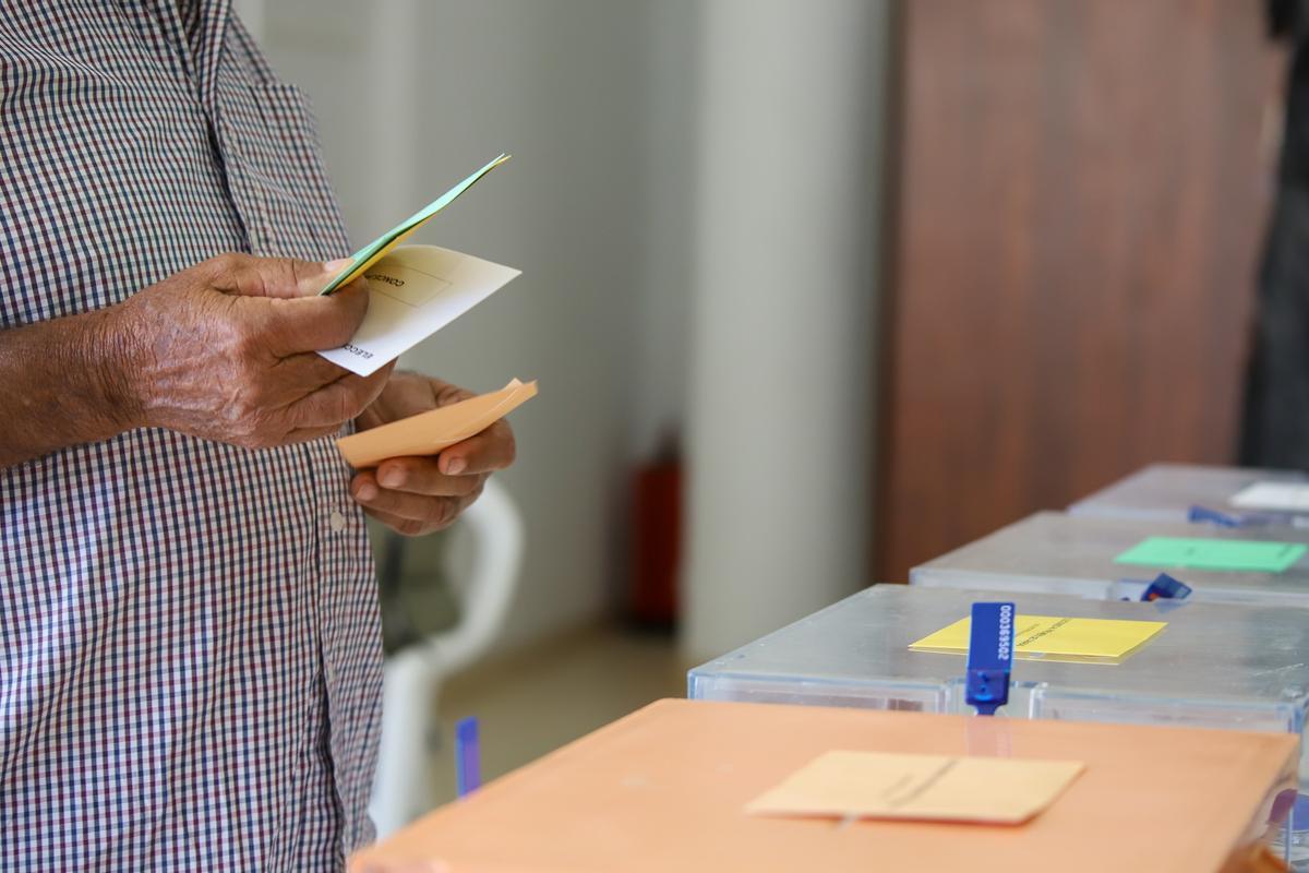 Un hombre sostiene sus papeletas de votación ante las urnas de la mesa en el colegio electoral este domingo 28 de mayo.