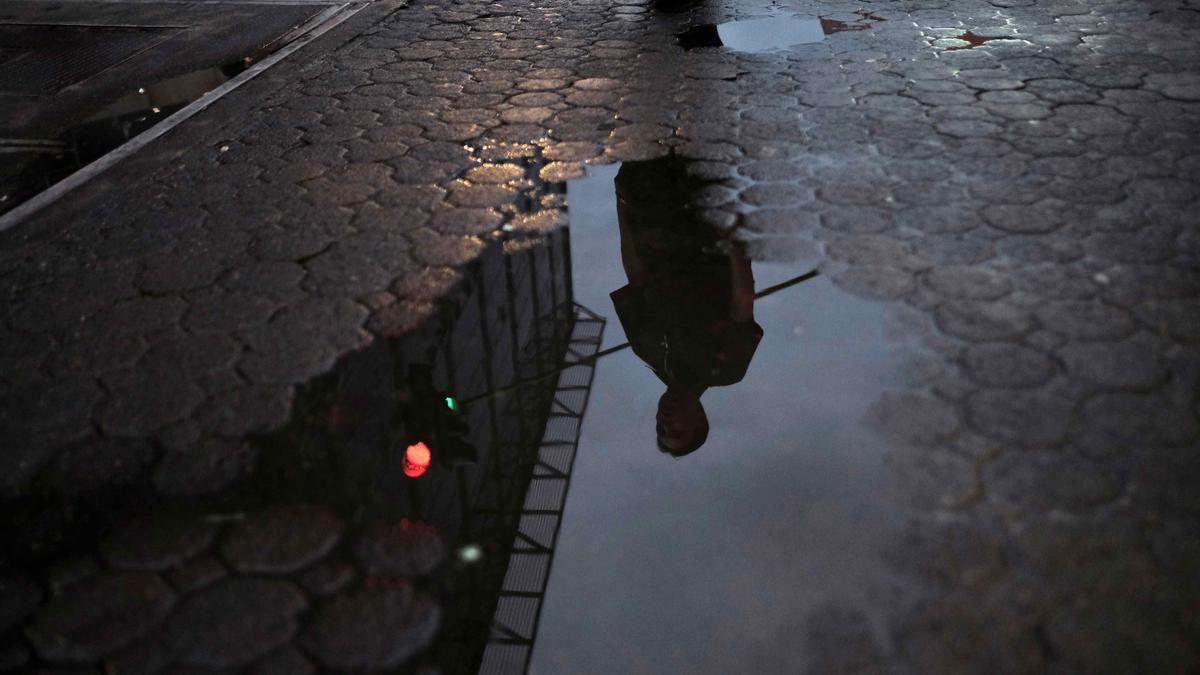 Un hombre pasea por una calle mojada por la lluvia.