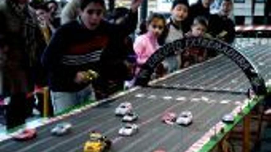 Jóvenes y mayores disfrutan con las carreras de coches eléctricos sobre railes en Villanueva