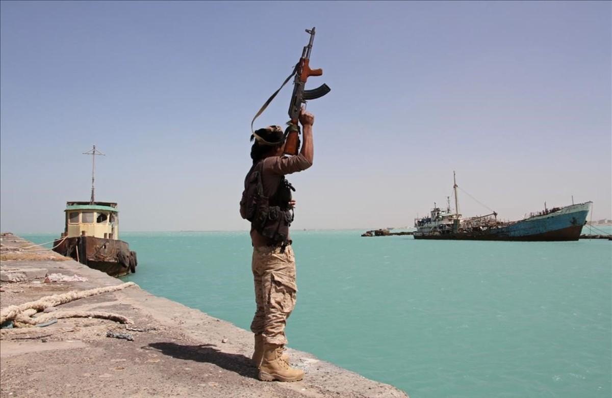 Un militar de las fuerzas gubernamentales respaldadas por Arabia Saudí levanta su arma frente al Mar Rojo, dominado por el otro lado por los huties.
