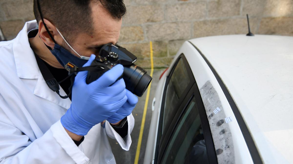 Un agente toma huellas dactilares en un vehículo y las fotografía junto a los testigos que muestran su tamaño.