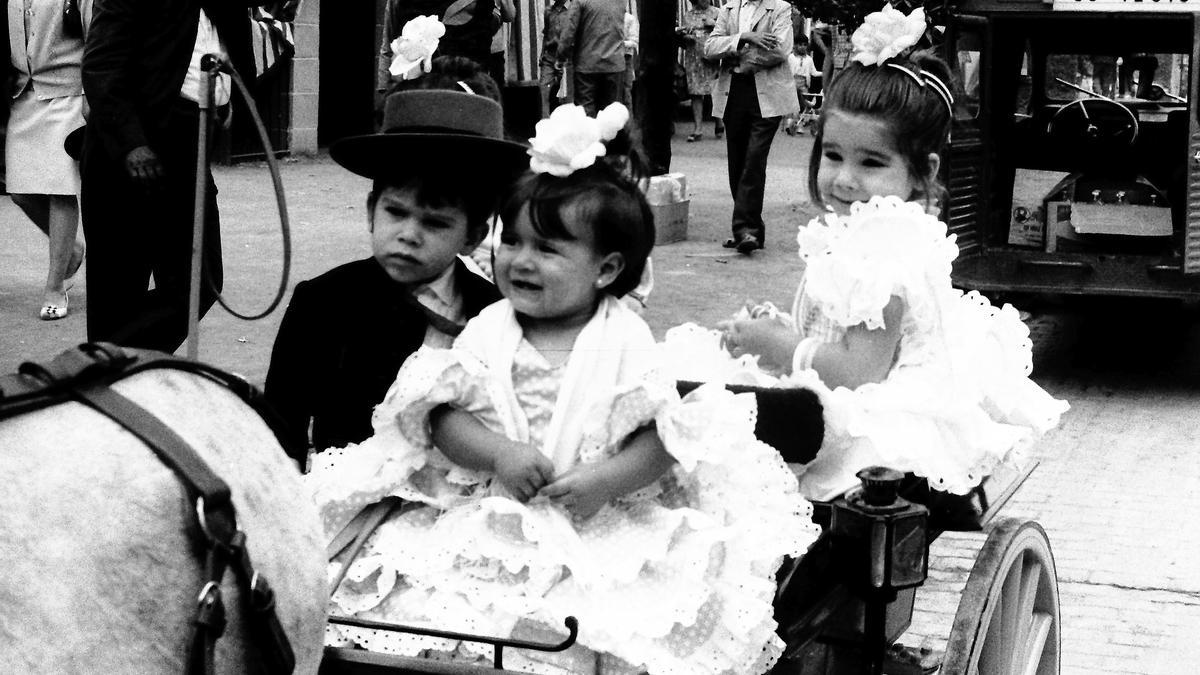 Feria de 1969 | Pequeños en un mini-coche tirado por un poni. Uno muy seriote, otra risueña y la del centro, con una sonrisa.