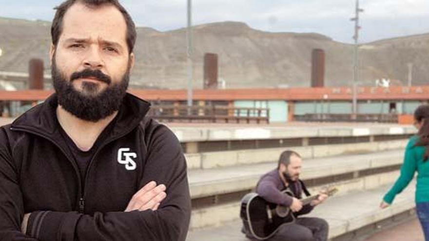 Ángel Martín (i) y Ricardo Castella, detrás, sentado, haciendo de músico callejero.