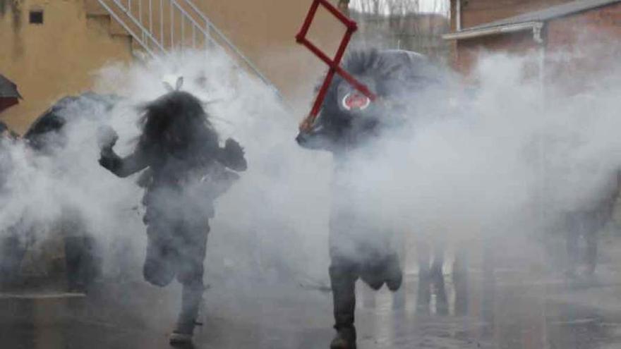 Los diablos durante su recorrido por las calles de Riofrío de Aliste y personajes de la tradicional mascarada en pleno festejo .