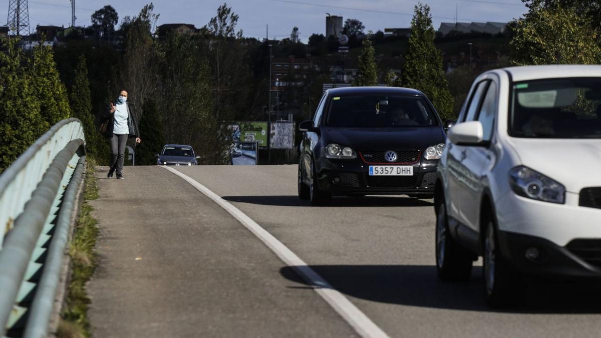 Una peatona avanza junto al tráfico por el puente sobre la carretera AS-17 que une Lugones y La Fresneda. | LNE