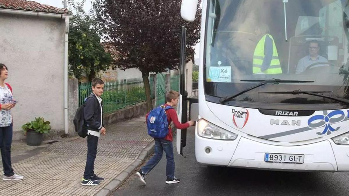 Dos alumnos suben a un autobús de transporte escolar en una de las rutas que conectan los núcleos rurales con los centros educativos.