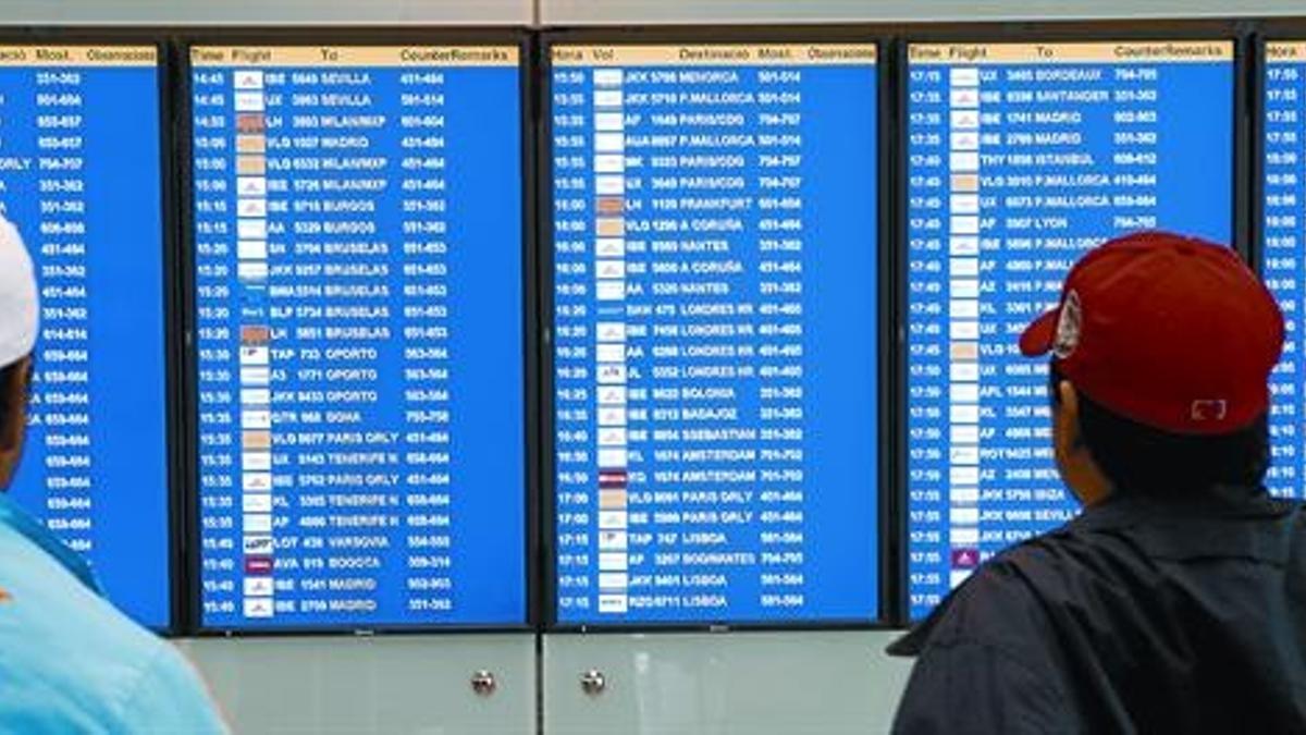 Dos pasajeros observan las pantallas de información del aeropuerto de El Prat, ayer, donde, después de tres días de caos aéreo, todos los vuelos salían con normalidad.