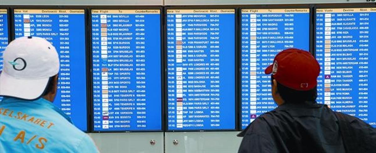 Dos passatgers observen les pantalles d’informació de l’aeroport del Prat, ahir, on, després de tres dies de caos aeri, tots els vols sortien amb normalitat.