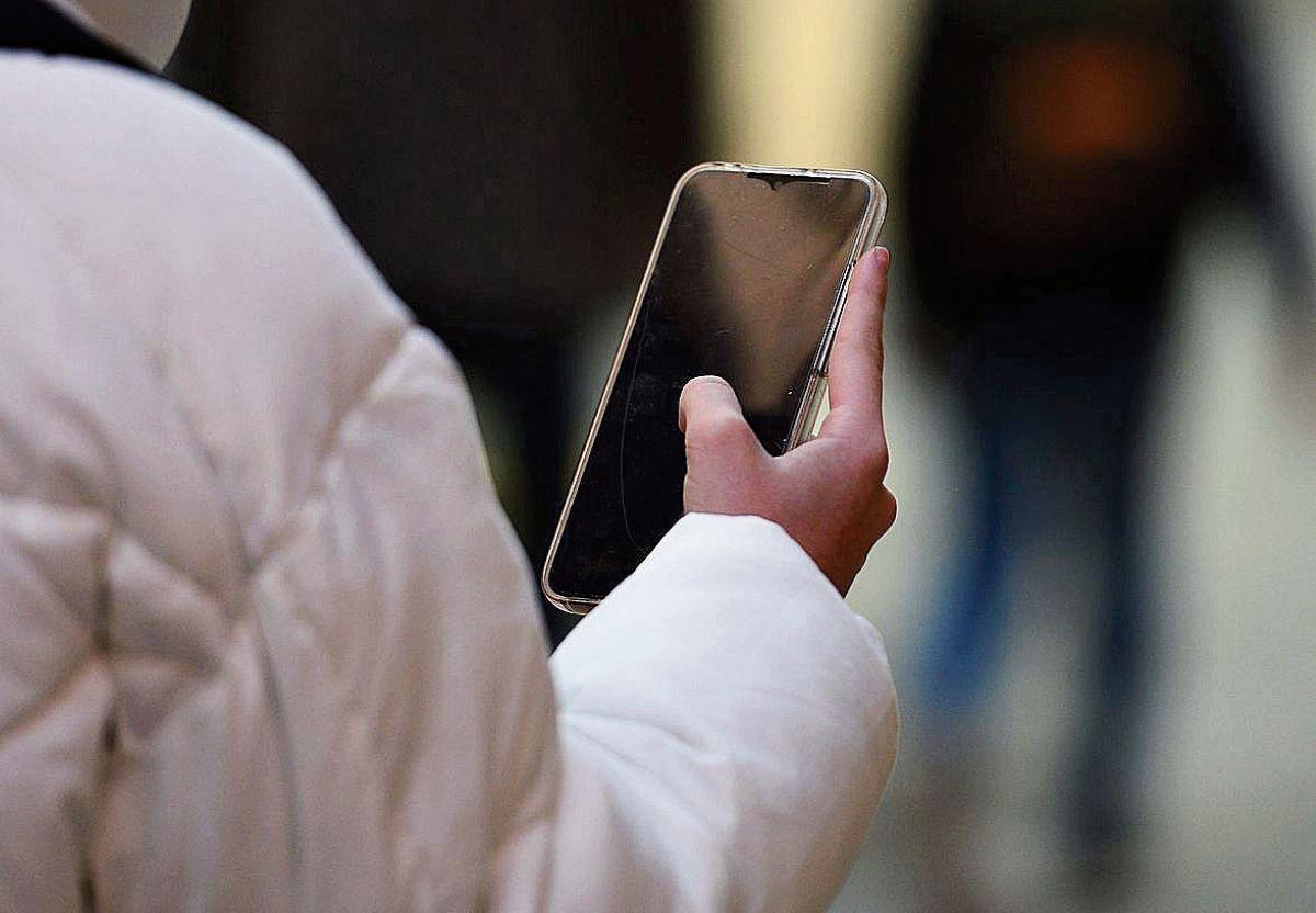 Una chica con un móvil en la mano.