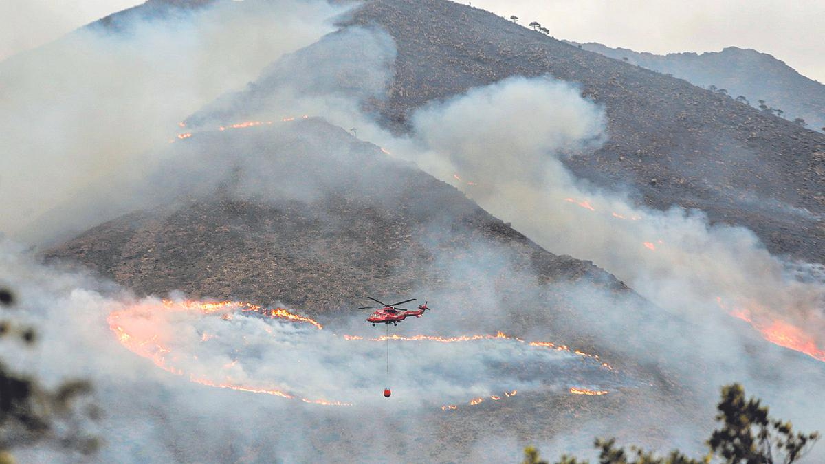 Un helicòpter llança aigua sobre les flames que assolen Sierra Bermeja