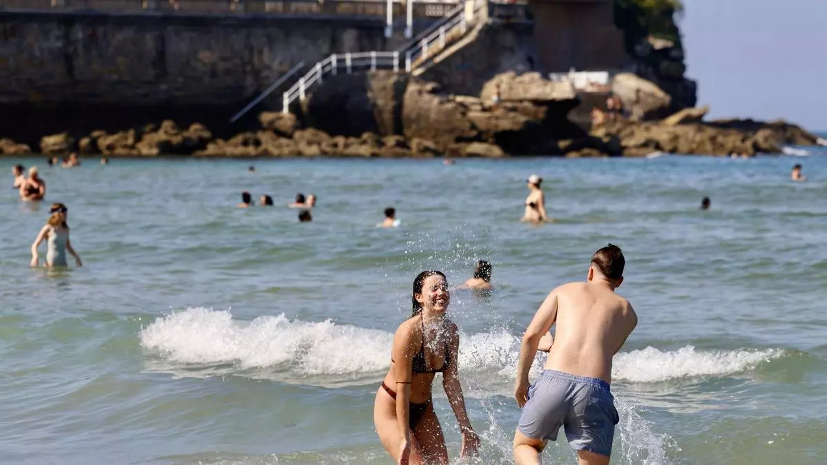 San Lorenzo se llena de bañistas para combatir el calor en Gijón: “Cuesta entrar, pero luego se está genial”