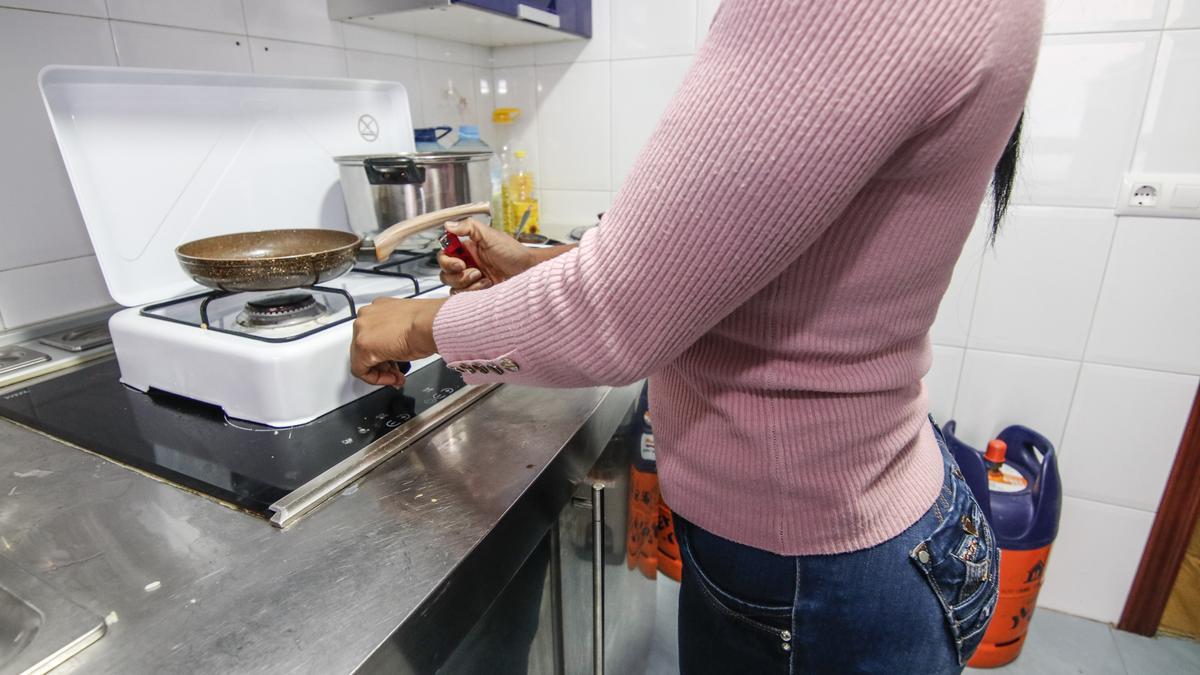 Una mujer enciende una cocina de butano colocada sobre una vitrocerámica, en 2021.