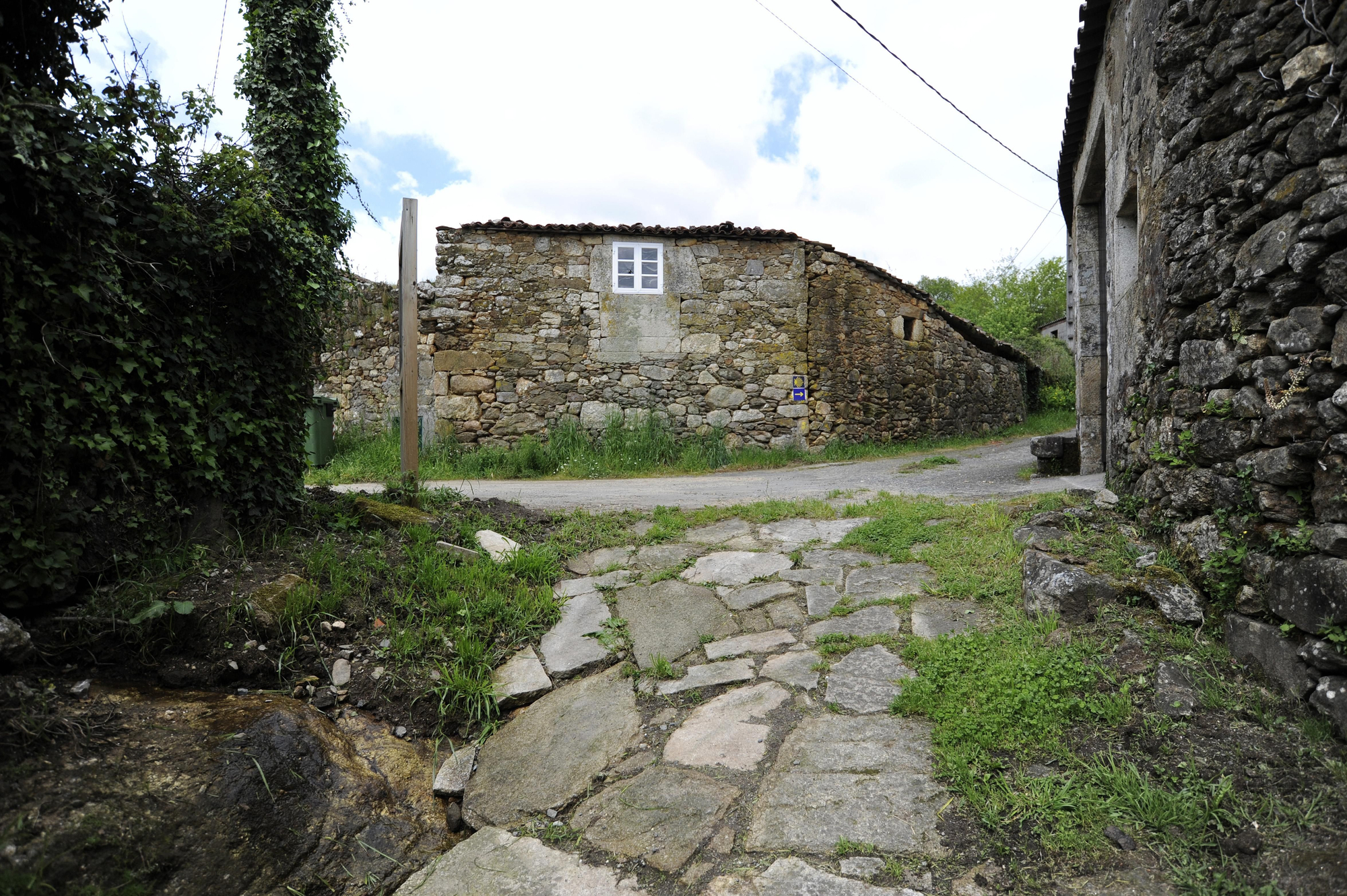 Un tramo del Camino de Santiago, con agua entre las piedras en su acceso a Taboada.